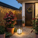 Decorative outdoor setting with potted plants, a lantern, and a wreath on a door.