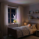 Lumi A002 boy rabbit solar garden ornament glowing RGB rainbow light on a child's bedroom windowsill at night with a sleeping toddler in bed