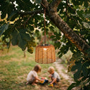 PT0907 Solar Pendant Light suspended from a fig tree branch in a backyard garden, with two children playing softly blurred in the background. Warm glow enhances family-friendly outdoor ambiance — ideal for gardens, patios, or tree-mounted installations.