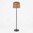 Modern rattan floor lamp with a woven basket shade and sleek black metal stand, featuring a round base.