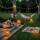 Friends enjoying guitar music on lawn with PT0906 solar lanterns, picnic blanket, string lights, cozy outdoor party ambiance