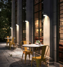 Outdoor patio area with tables and chairs under streetlights at night.
