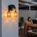 Kasa Duo PT0910 solar wall light with two PE rattan lanterns on one bracket, casting layered shadows on white stucco wall — ideal for patio or entryway ambiance with warm 3000K glow and IP54 weatherproof design.