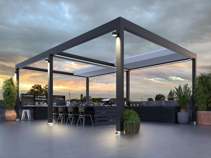 Modern outdoor patio pergola with a dark metal frame, retractable roof panels, integrated lighting, and an attached bar counter with dining chairs, shown on a rooftop at dusk.