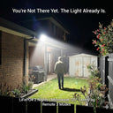Person walking towards a house with a bright light shining on the exterior, promoting a security light system.