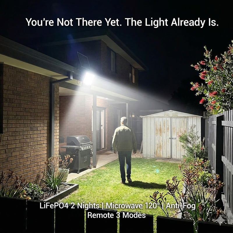 Person walking towards a house with a bright light shining on the exterior, promoting a security light system.