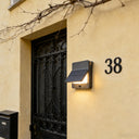 Solar-powered wall light fixture on a beige building exterior with house number 38.