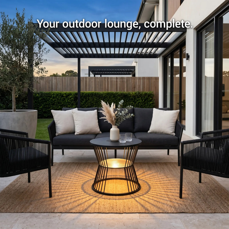 Outdoor lounge area with black sofa, chairs, and table on a patio.