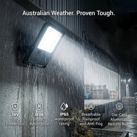 The E017EI Fano LED Floodlight operating brightly in heavy rain at night, proving its IP65 waterproof rating and die-cast aluminum construction designed to withstand harsh Australian weather conditions.