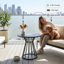 Woman sitting on a couch with a dog on a balcony overlooking a cityscape