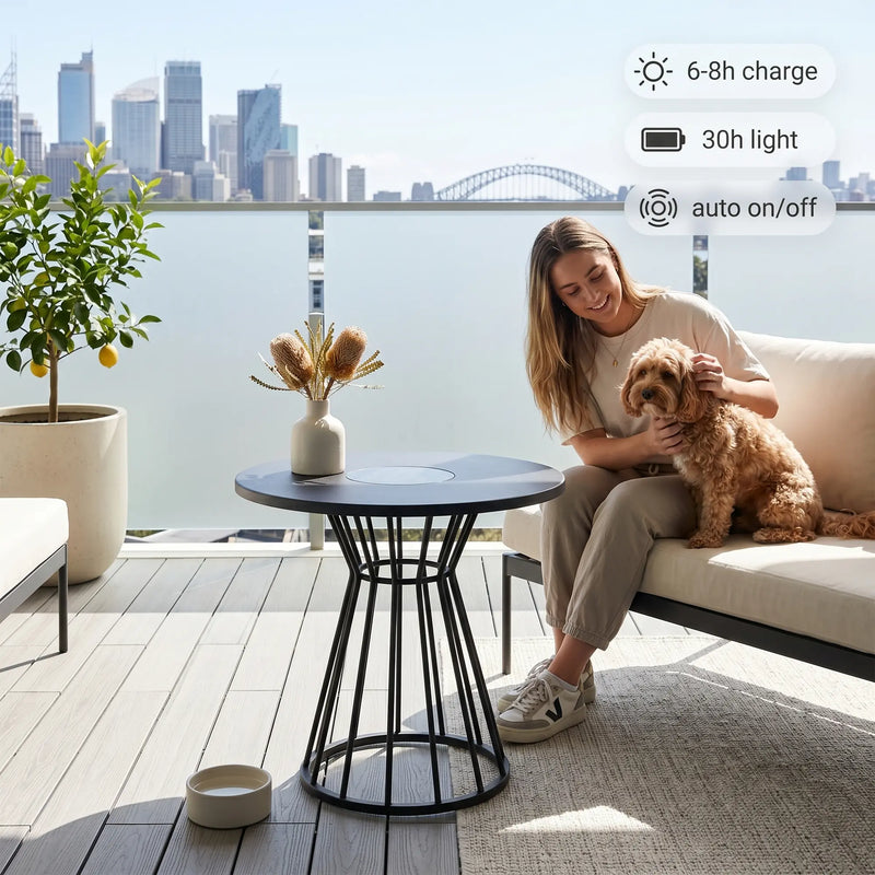 Woman sitting on a couch with a dog on a balcony overlooking a cityscape