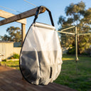 Translucent solar shower bag hangs outdoors; water level visible inside, demonstrating capacity and sun-powered heating design.