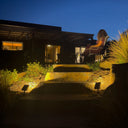 solar spotlight pair warm amber uplighting natural stone steps garden bed night Australian backyard close up