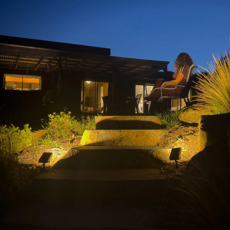 solar spotlight pair warm amber uplighting natural stone steps garden bed night Australian backyard close up