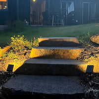 solar spotlight warm glow stone steps garden night Australian backyard woman sitting patio uplighting landscape