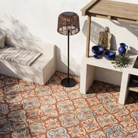 Rattan solar lamp beside concrete bench and blue ceramics on patterned tile floor.