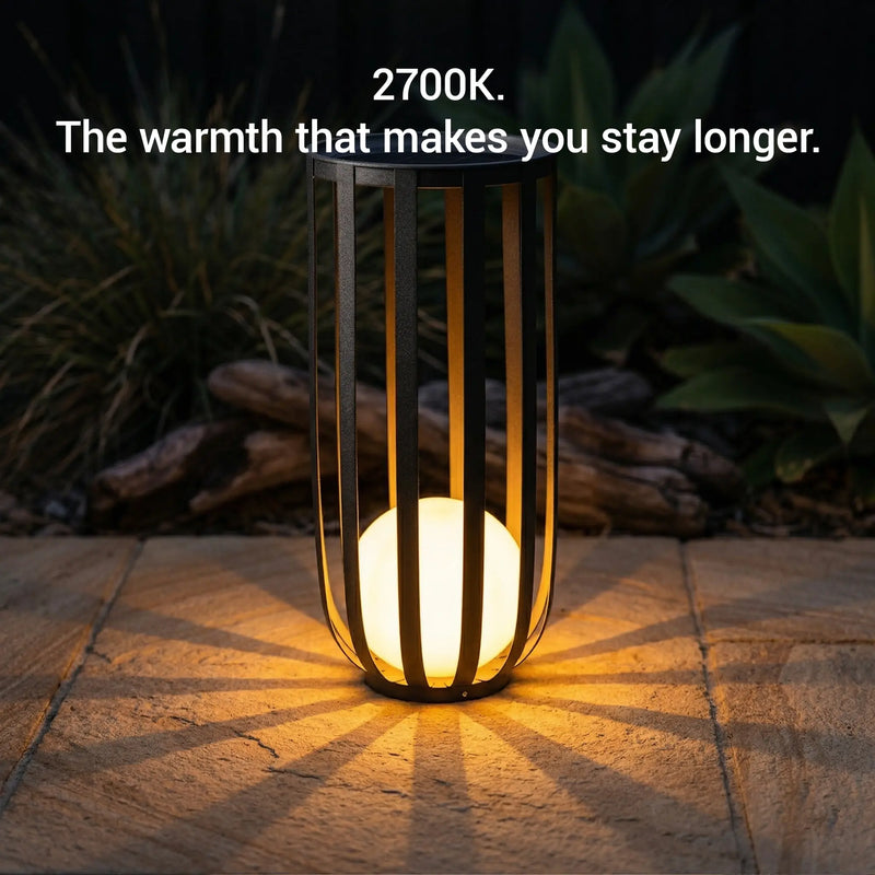 Decorative outdoor light with warm glow on a stone surface, surrounded by plants.