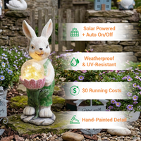 A solar-powered rabbit garden statue holding a crackle glass light globe, displayed in a garden setting with text callouts highlighting four features: Solar Powered + Auto On/Off, Weatherproof & UV-Resistant, $0 Running Costs, and Hand-Painted Detail.