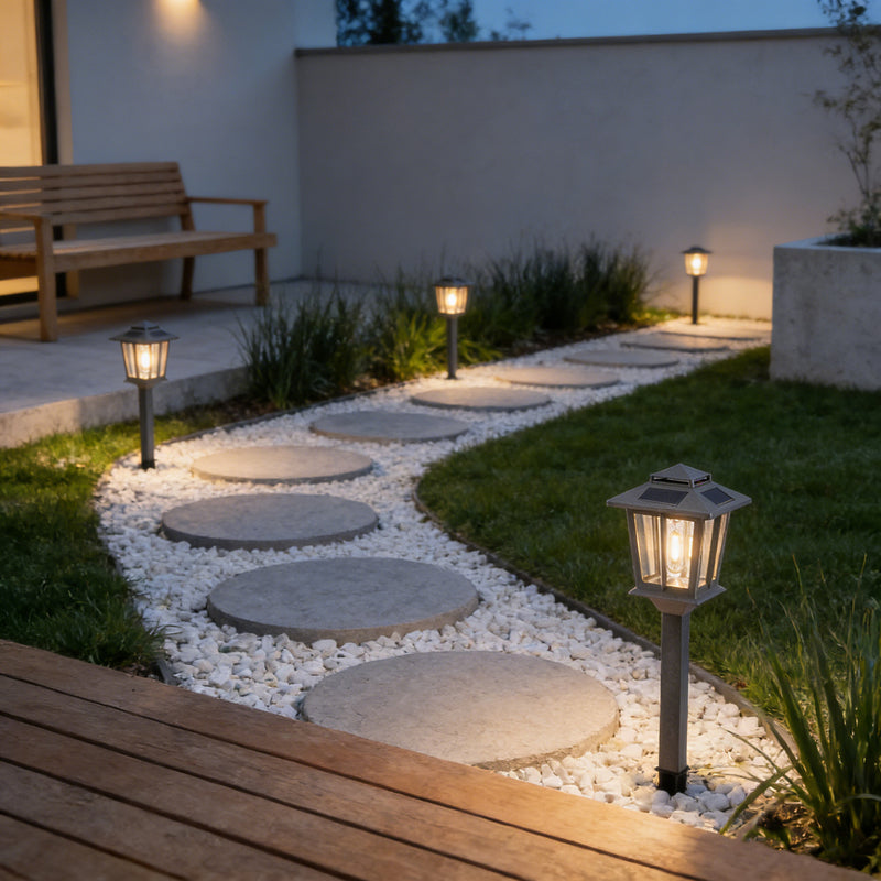 Outdoor garden pathway with stepping stones and outway illuminated lanterns at dusk.