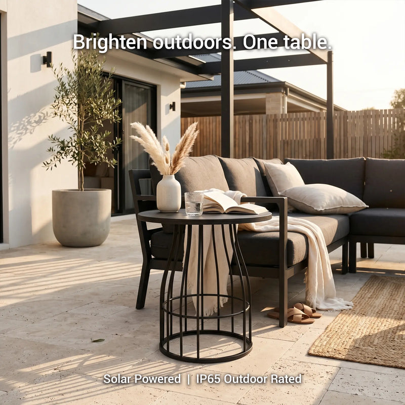 Outdoor patio setting with a black table, sofa, and decor elements on a wooden deck.