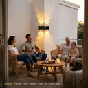 A family of four enjoying dinner on an outdoor deck, with the PT0803 Grivo solar corner light providing warm, ambient illumination on the white wall behind them. The text '3000K · Flicker-Free · Warm Light for Every Age' emphasizes its eye-friendly, anti-glare design perfect for family gatherings.