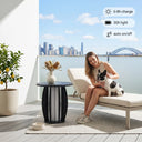 Woman sitting on a lounge chair with a dog on a balcony with a cityscape view.