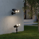 Outdoor wall and ground solar spotlights on a building exterior with grass and a tree.