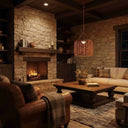A cozy rustic living room with a stone fireplace, warm wood ceiling beams, a woven pendant light, a leather armchair, a wooden coffee table, and a cream sofa with plaid pillows.