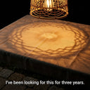 Wooden table with woven lampshade casting circular shadows on a dark background