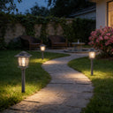 Solar-powered outdoor lamps illuminating a stone pathway in a garden.