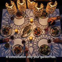 Dining table set with plates of food, candles, and people eating in a cozy setting.