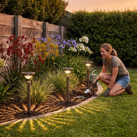 Flowerbed accent: woman installs solar lamps along garden edge, enhancing blooms with soft light.