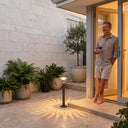 Patio elegance: man enjoys wine beside glowing lamp, casting radiant shadows on stone tiles.