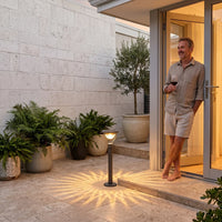 Patio elegance: man enjoys wine beside glowing lamp, casting radiant shadows on stone tiles.