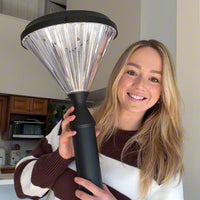 Person holding a large black and silver light in a kitchen setting