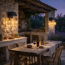 Warm glowing solar wall fixture with wicker shades on stone patio at dusk