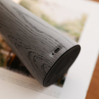 Close-up of a cylindrical electronic device with wood grain texture on a blurred background