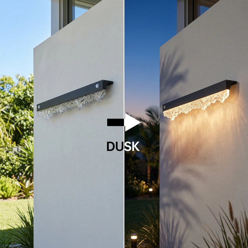 Outway Solar Outdoor Wall Light auto dusk-to-dawn activation – unlit aluminium alloy unit on white rendered pillar in daylight (left), automatically glowing warm 3000K white at dusk (right)