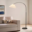 Floor lamp next to a white sofa with a decorative pillow in a living room setting.