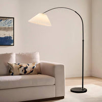Floor lamp next to a white sofa with a decorative pillow in a living room setting.