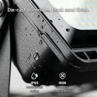 E027EI Voro close-up of die-cast aluminium housing with black sand finish, water droplets beading off the surface, IP65 waterproof and IK06 impact resistance badges