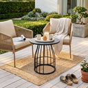 Outdoor seating area with two chairs, a small table, and a rug on a wooden deck.