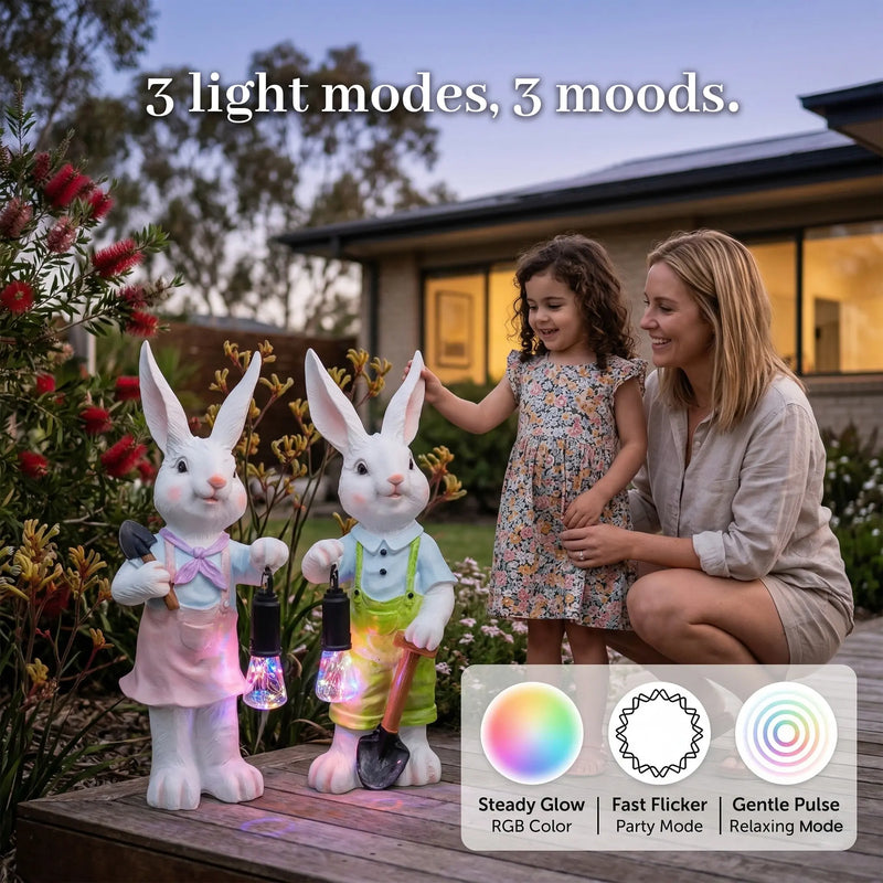 A mother and young daughter admiring two white resin rabbit garden ornaments with RGB lanterns on a backyard deck at dusk, with an inset graphic showing three light modes: Steady Glow RGB Color, Fast Flicker Party Mode, and Gentle Pulse Relaxing Mode, with text overlay 3 light modes 3 moods