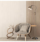 Modern interior with a gray armchair, side table, and floor lamp against a neutral wall.