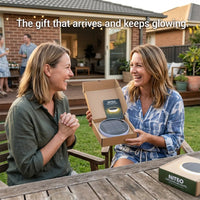 Woman opening a Niteo solar light gift box in a backyard setting, showing the premium packaging of the solar garden light kit.