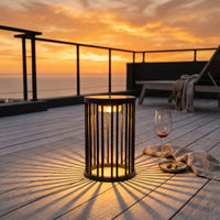 Sunset over a deck with a lit lantern and glass of wine.