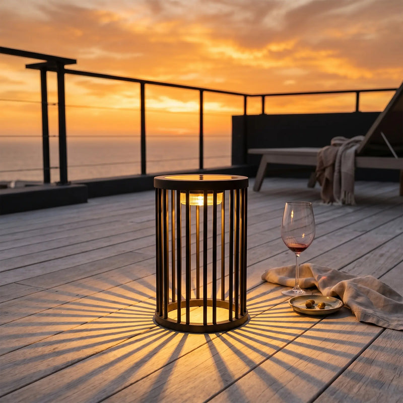 Sunset over a deck with a lit lantern and glass of wine.