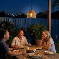 Couple enjoying wine and conversation under PT0913 pendant in garden setting at twilight — blue corrugated fence backdrop highlights ambient lighting and relaxed evening atmosphere with remote-controlled brightness.
