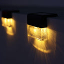 Solar wall light fixtures mounted on a dark exterior wall, glowing with warm yellow light in the night.