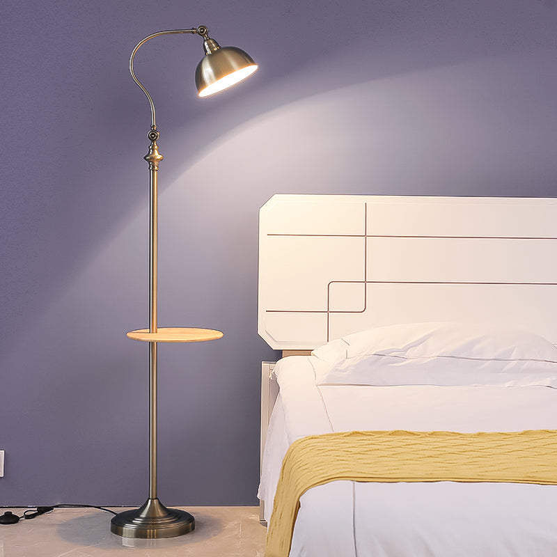 Gold floor lamp with a round table next to a bed with white bedding and a yellow blanket.